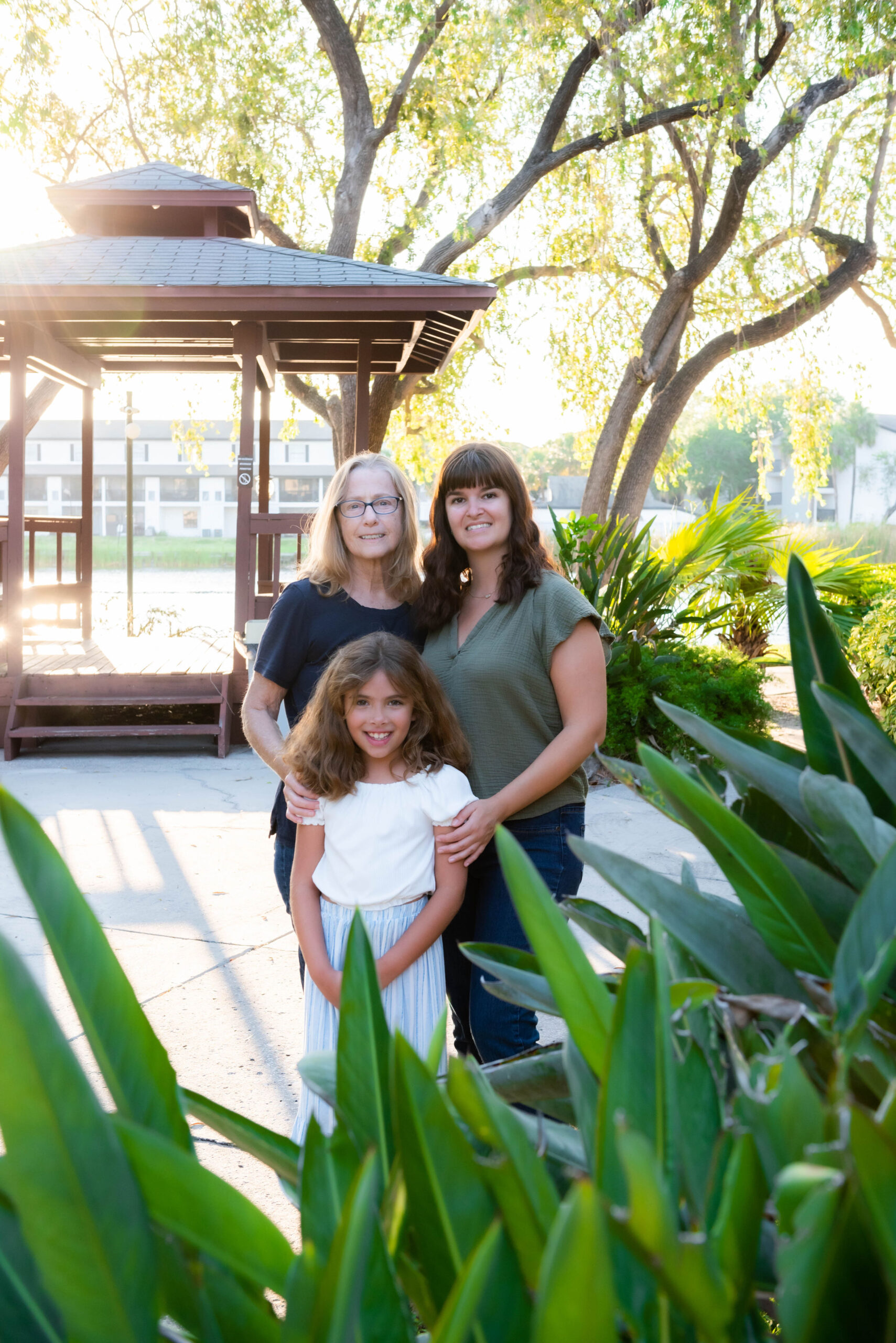 Three generations of women standing in a garden near a gazebo.