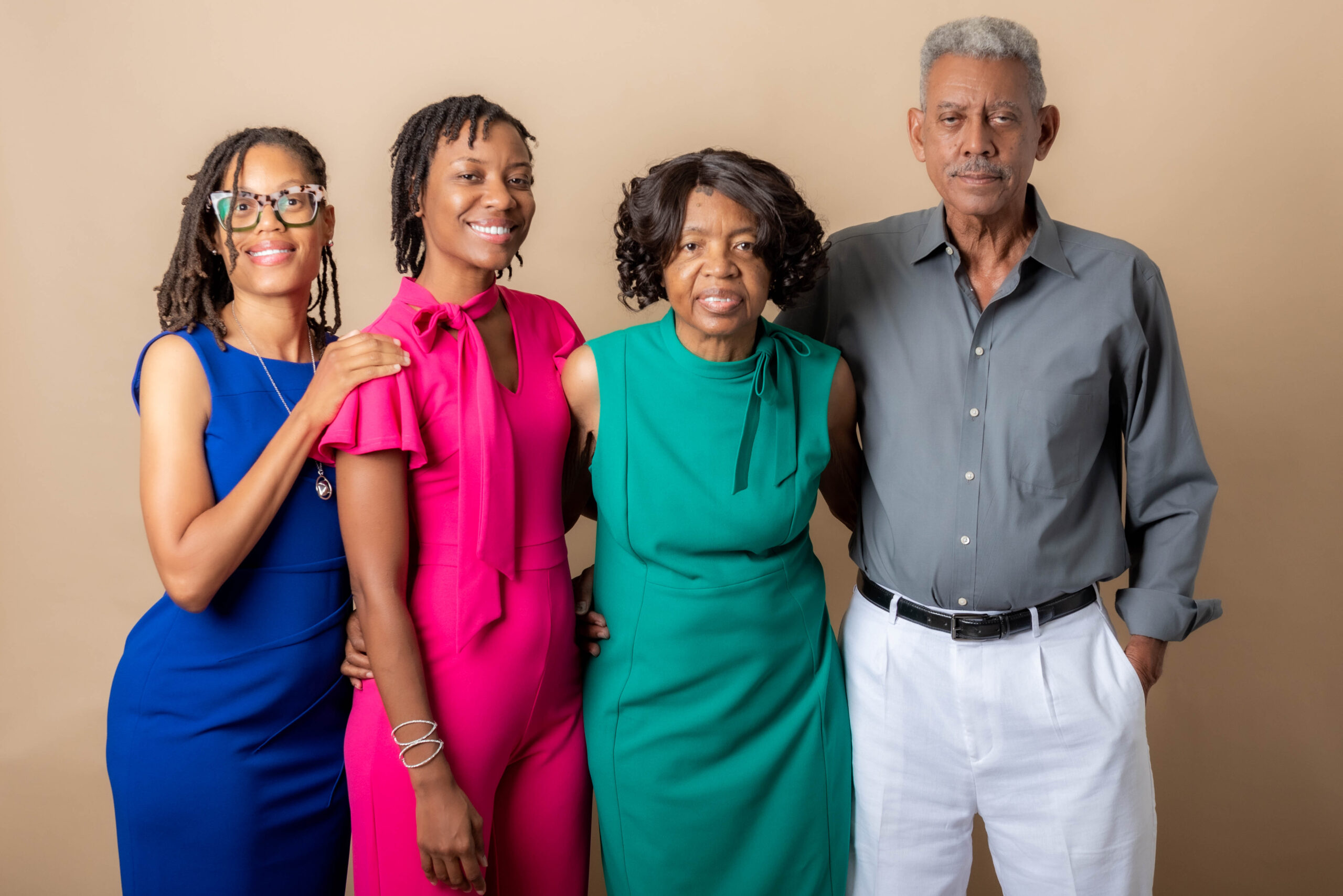 A family portrait featuring two women, a man, and an elderly woman posing together in a studio setting.